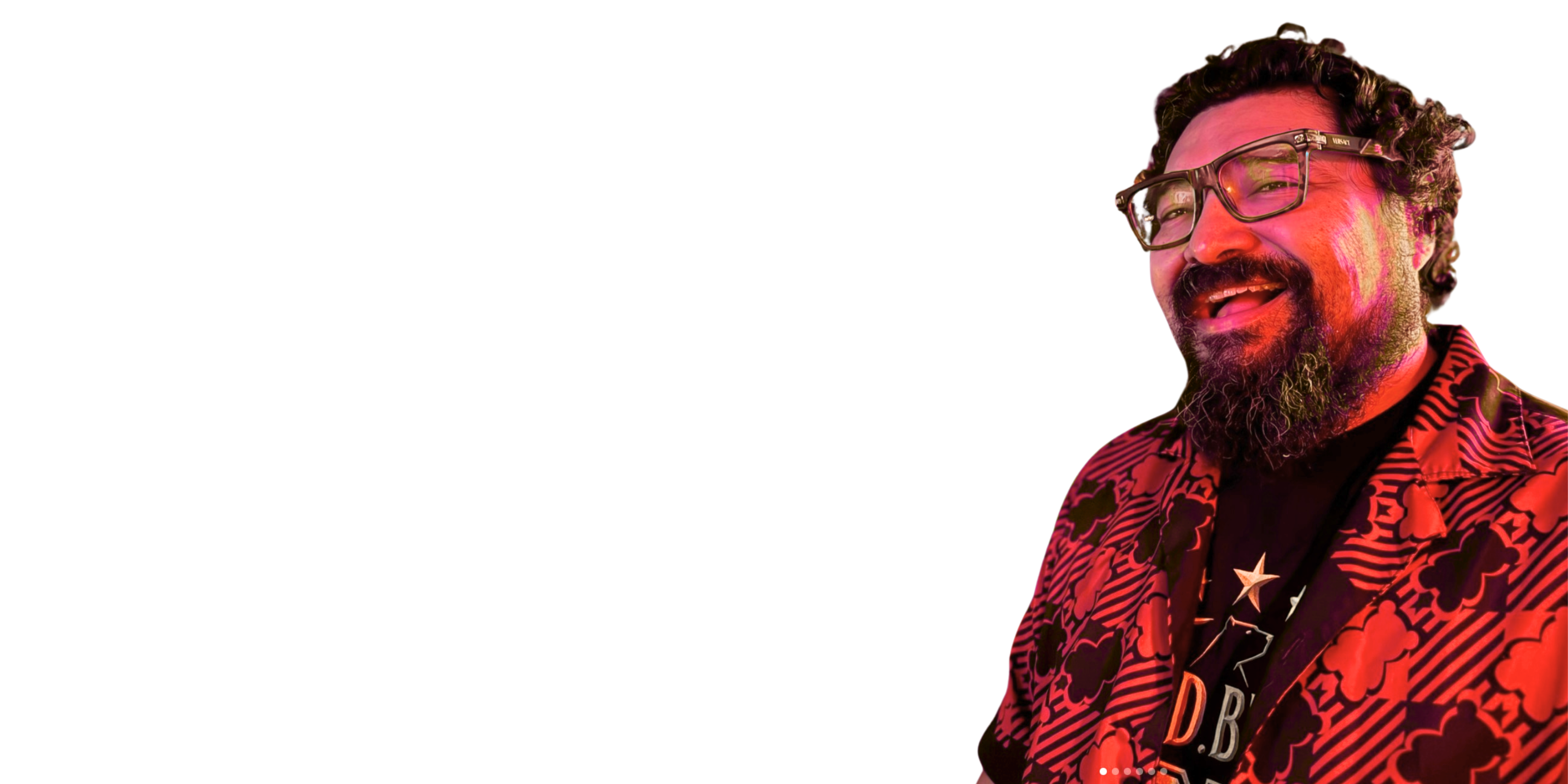 Person with glasses and a patterned shirt under red lighting on a white background