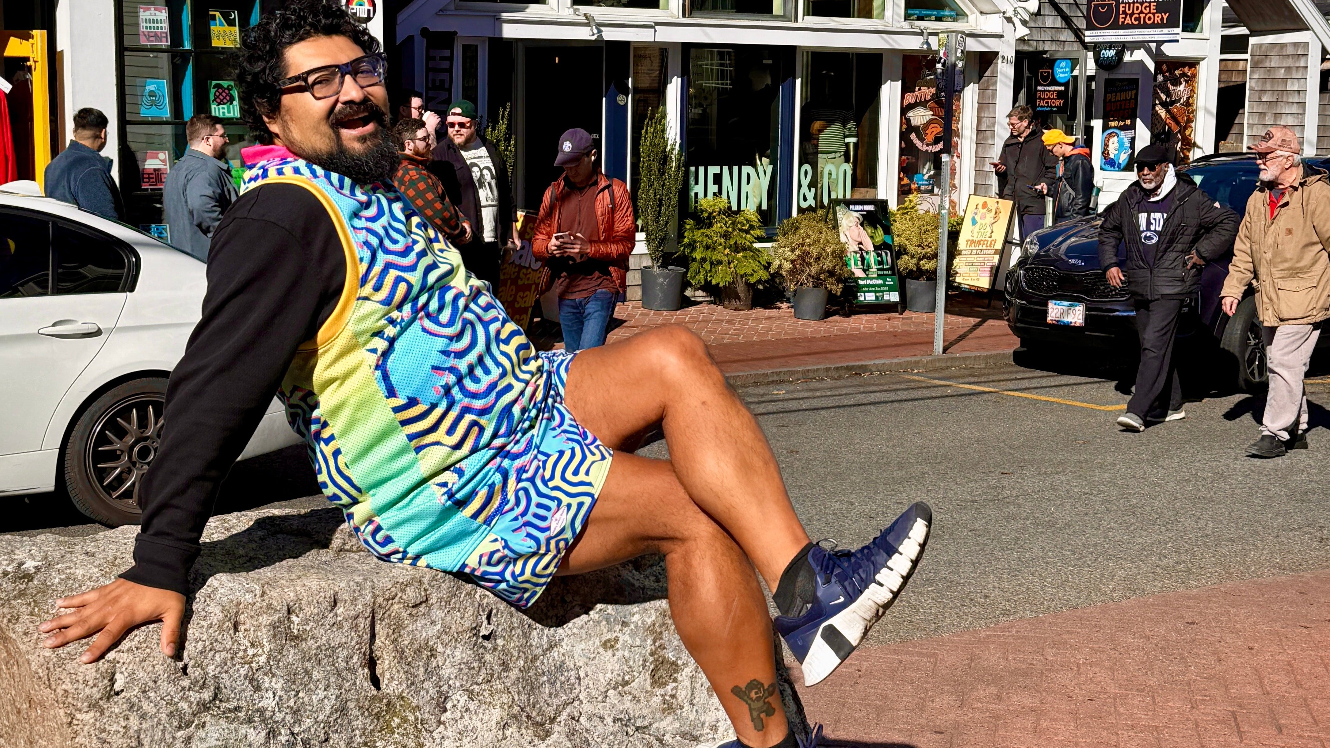Man sitting on a rock in an urban setting with shops and people in the background