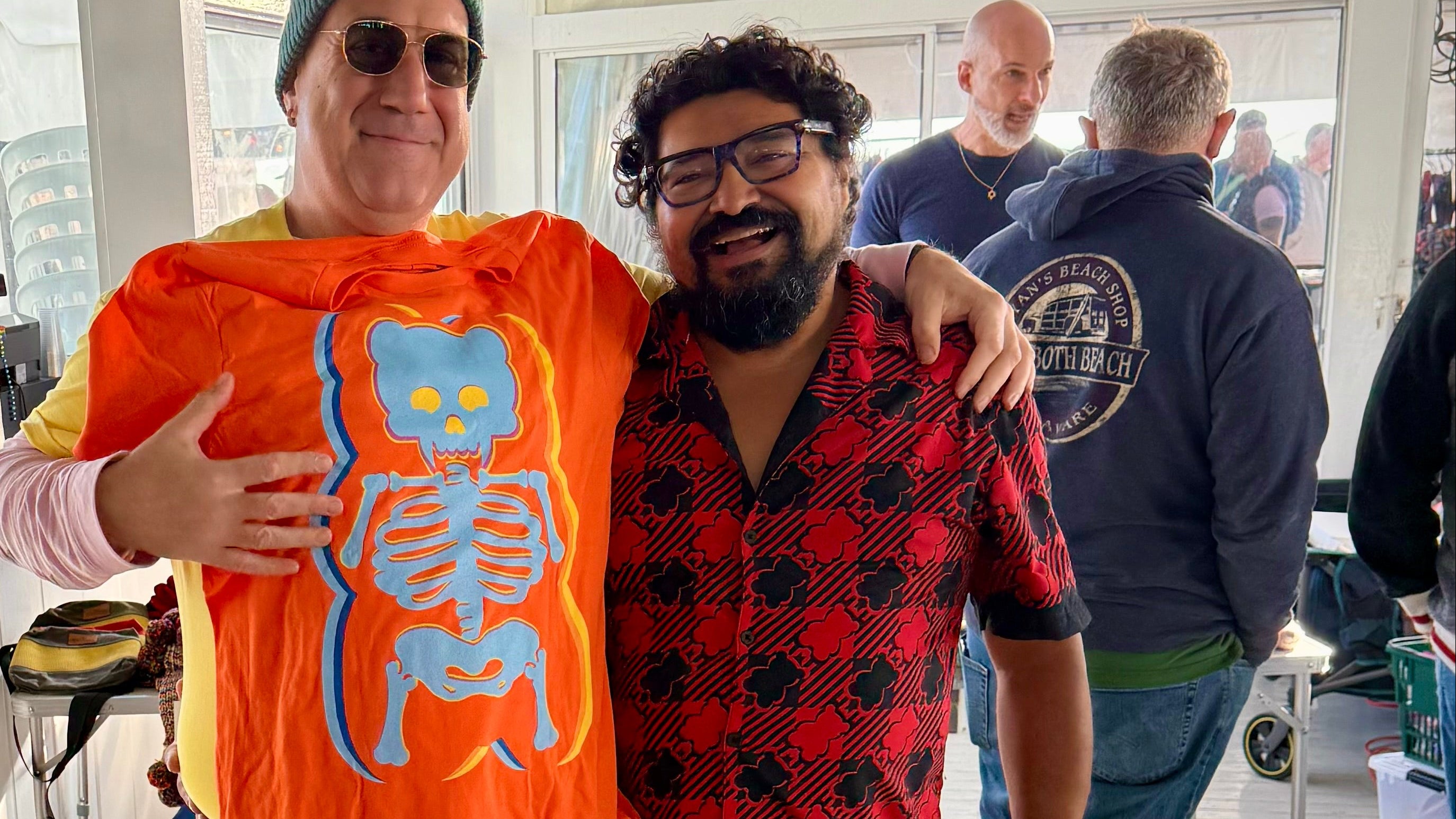 Two people standing next to a table with colorful shirts in a store setting.