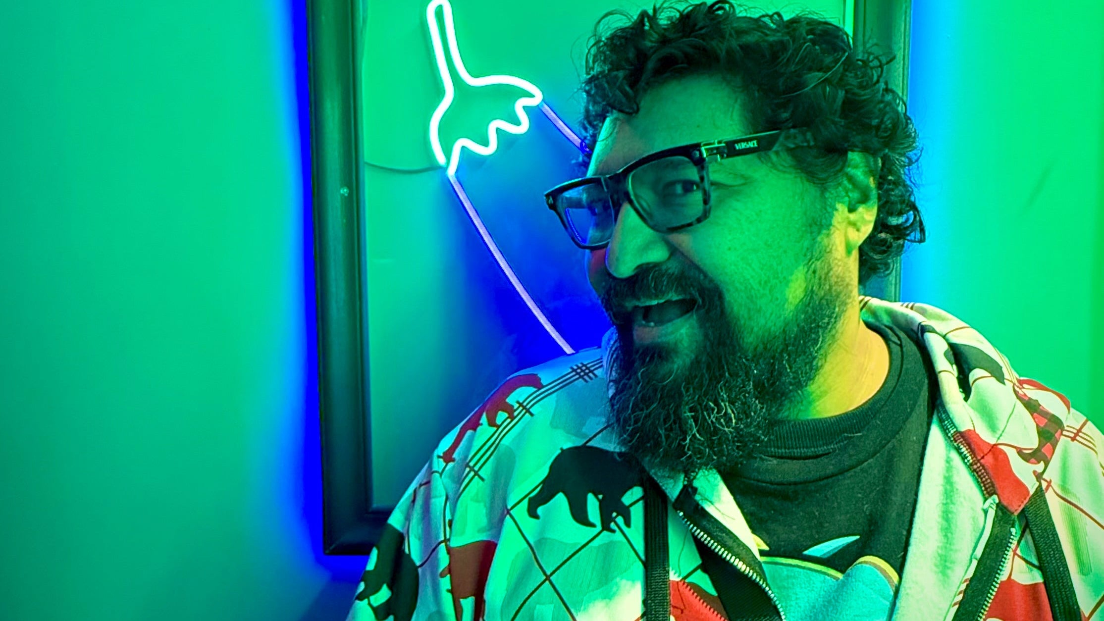 Man with glasses standing in front of a green neon sign with 'boyberry' branding.