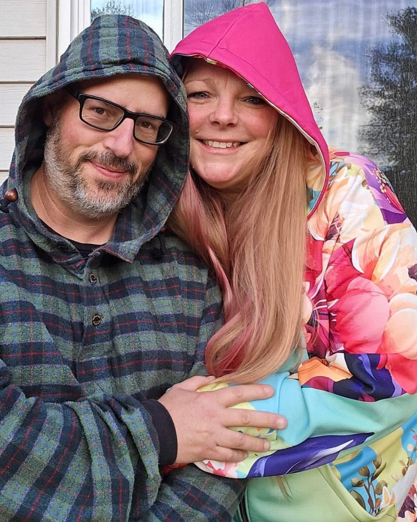 Two people wearing colorful hoodies standing close to each other outdoors.